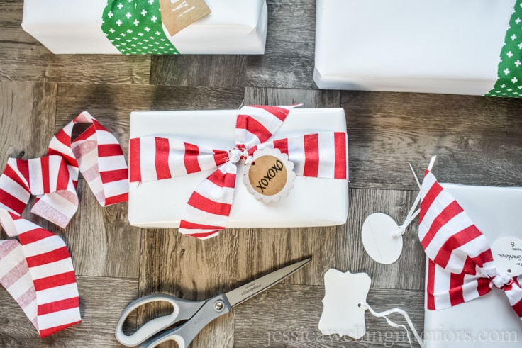 Christmas gift wrapping with white paper and candy cane striped fabric bows.