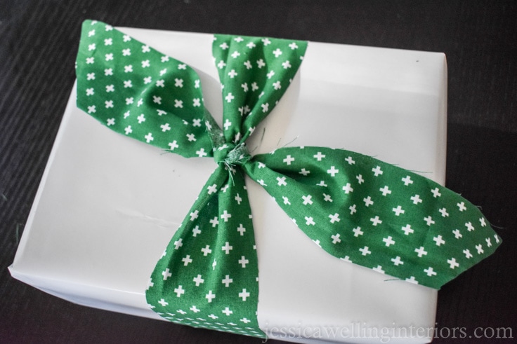 Christmas gift wrapping with white paper and green fabric ribbon