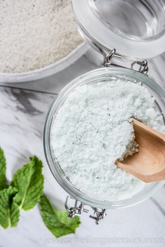 open jar of peppermint scented bath salts with a wooden scoop