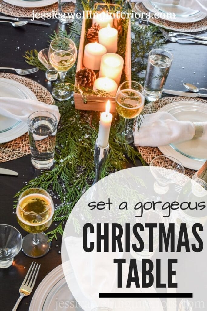 Set a Gorgeous Christmas Table: black table set with evergreen boughs, faux snow, candles, pine cones, and dinnerware with glowing candlelight