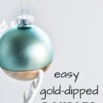 Easy Gold-Dipped Baubles: aqua and gold glass ball ornament hanging from a white tree branch