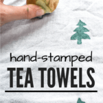 white tea towel with hand using potato stamp to print green Christmas trees on the tea towel