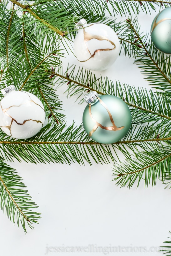 glass ball kintsugi Christmas ornaments with fir branches on a white background