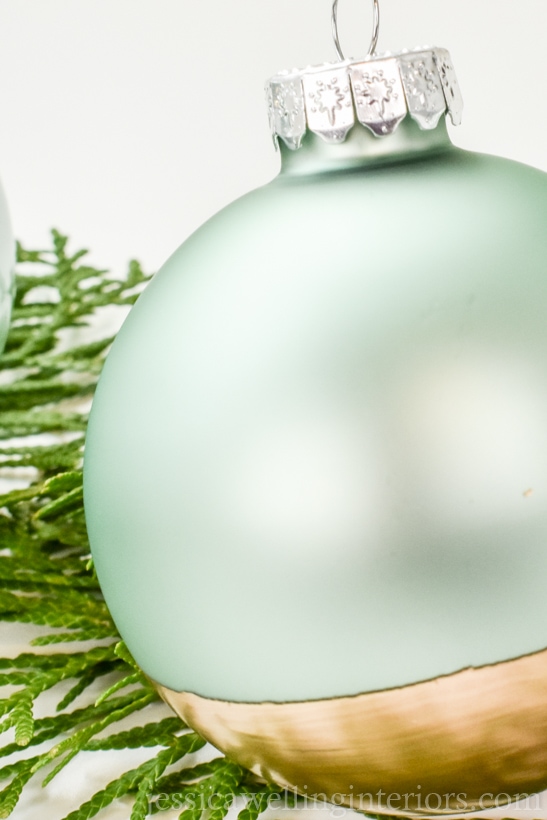 aqua glass bauble dipped in gold paint sitting on Christmas greenery
