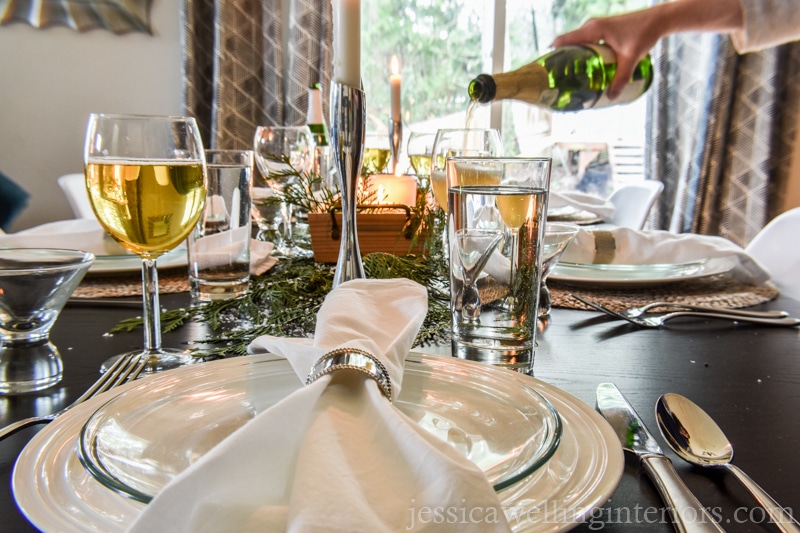 Christmas table setting with hand pouring sparkling cider into a glass