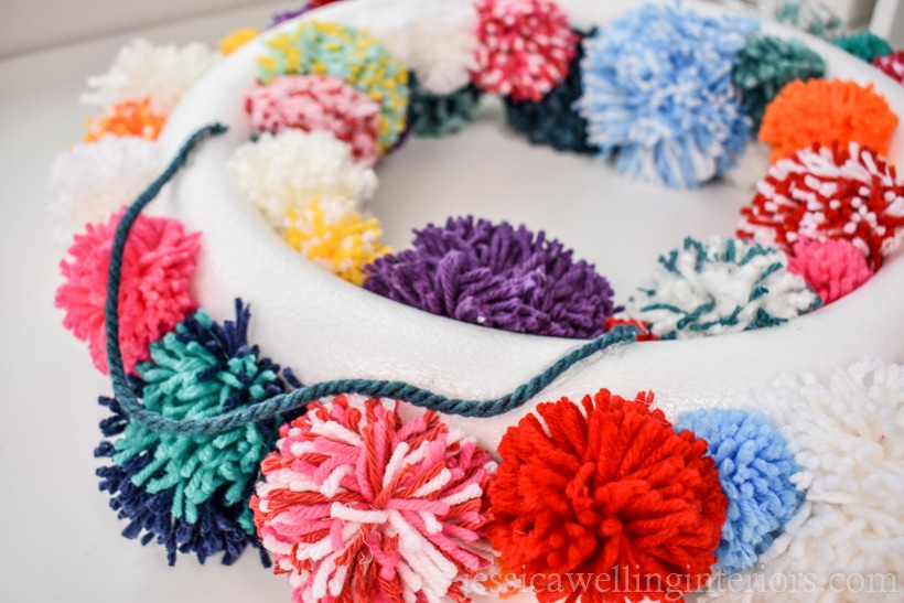 back side of pom pom wreath, showing how the hanger yarn is attached to the back of the styrofoam wreath form