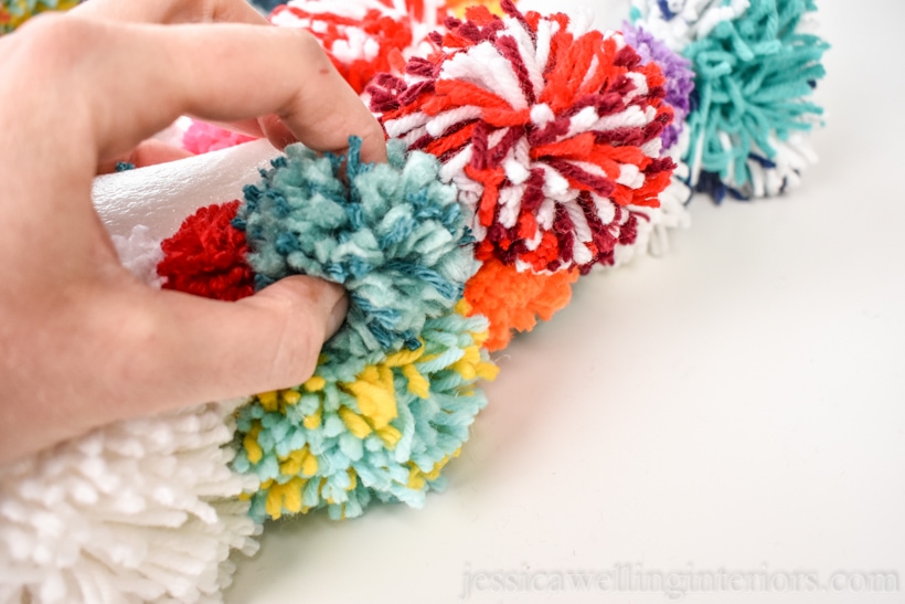 close-up of hand attaching a pompom to the wreath form