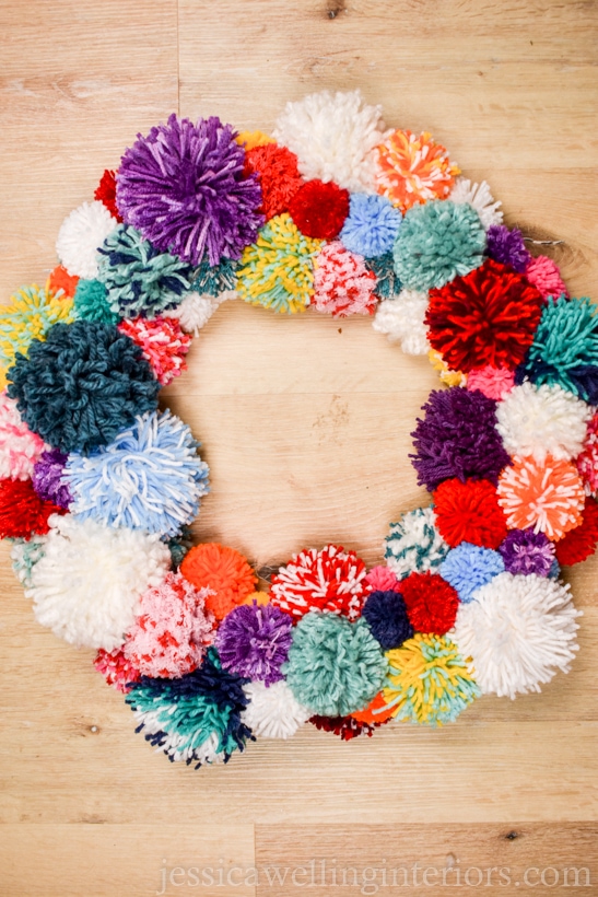 multicolored pompom wreath on a wood background