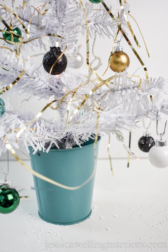 close-up of white dollar store mini Christmas tree decorated with gold tinsel and mini baubles