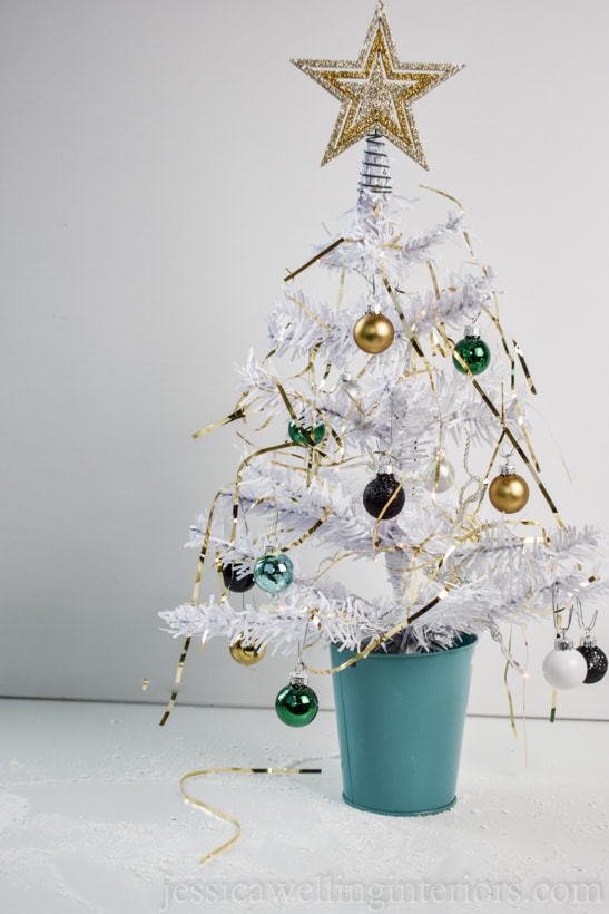 white mini Christmas tree with glam tinsel, lights, and baubles