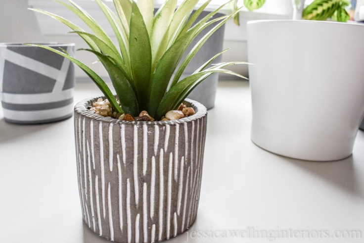 small concrete planter with a faux plant sitting on a white desk