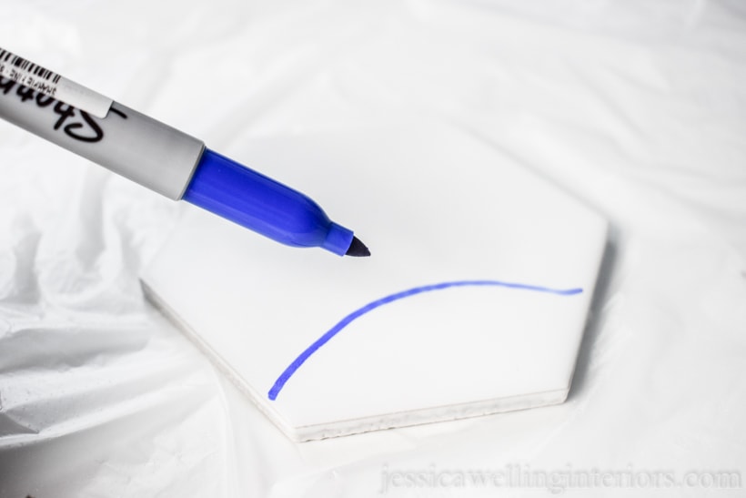 close-up of blue Sharpie pin drawing on a white tile to make DIY tile coasters