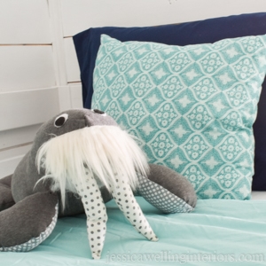 stuffed walrus sitting on an aqua-colored bunk bed