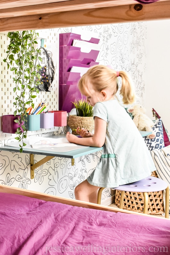 little girl working at a desk in a room with white painted walls and bright colored accessories- the best paint for dark rooms is white