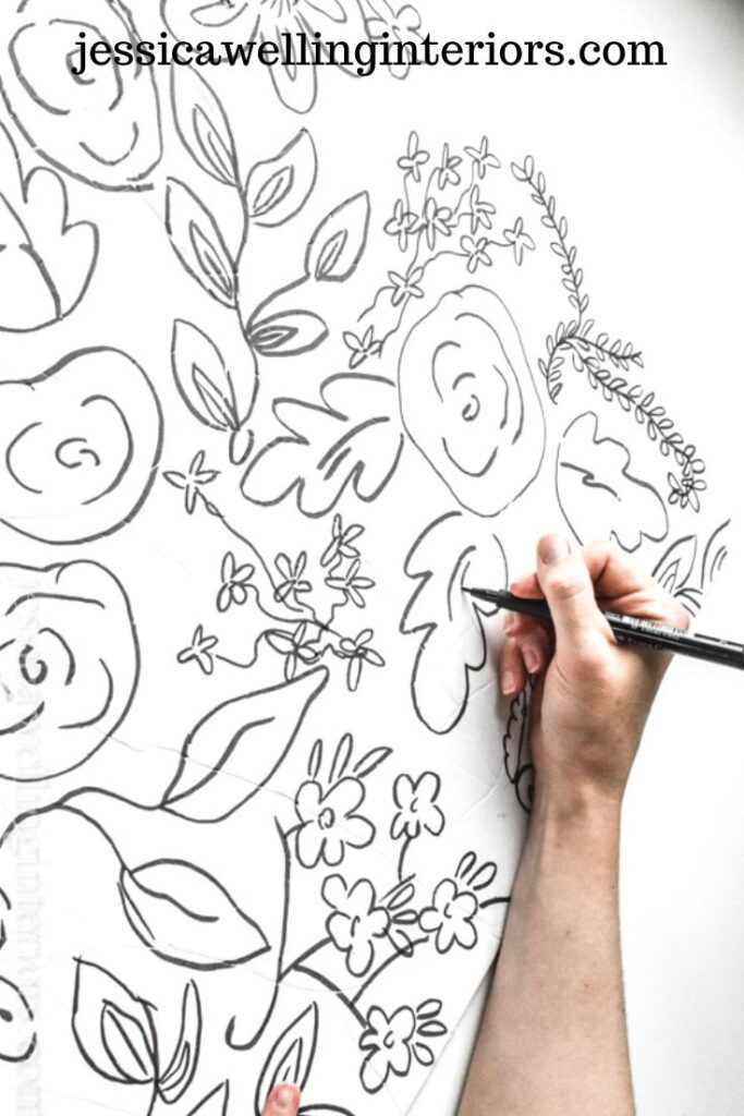 Easy DIY Faux Wallpaper: woman's hand drawing a floral print on a white wall with a Sharpie
