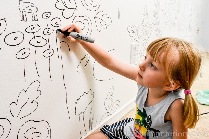 child drawing a pattern on the wall with a Sharpie to create a faux wallpaper accent wall