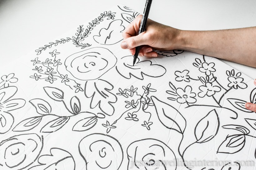 hand drawing whimsical floral pattern on tag board with  black marker to design diy wall art