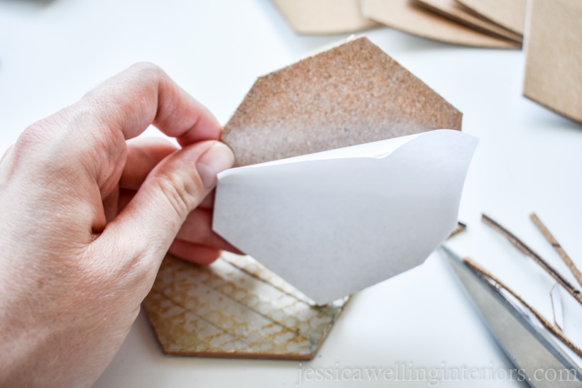 Hand peeling paper backing off of cork before attaching it to DIY coaster