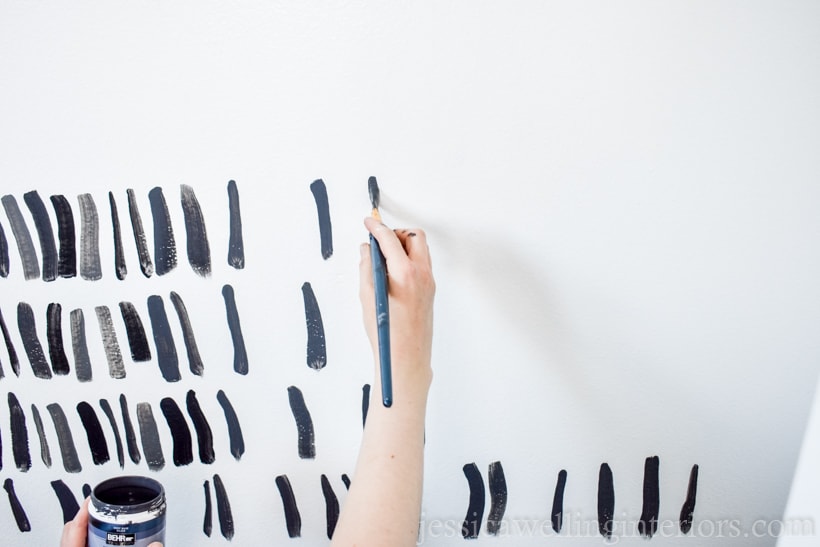 hand painting a grey brush strokes on a diy accent wall