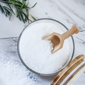 overhead view of jar of homemade bath salt with a wood scoop