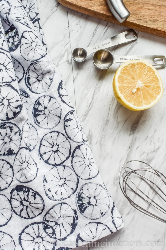 hand-stamped four sack towel on countertop with cutting board, measuring spoons, and a lemon half