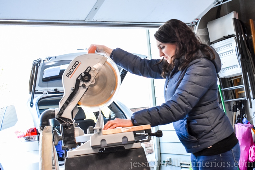 woman cutting board with a chop saw in a garage to make an indoor vertical garden planter