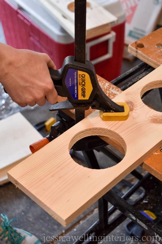 close-up of hands clamping vertical garden shelf to workbench