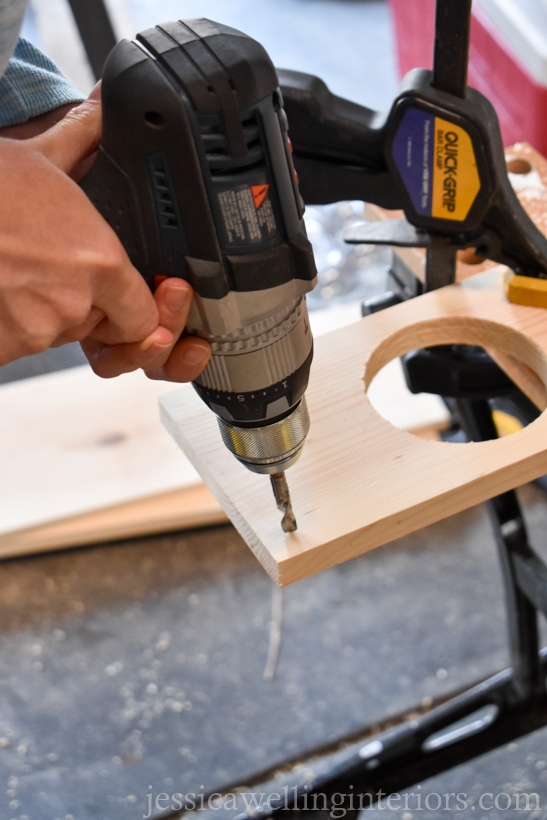 close-up of handing using drill to drill holes in a wood vertical wall garden shelf