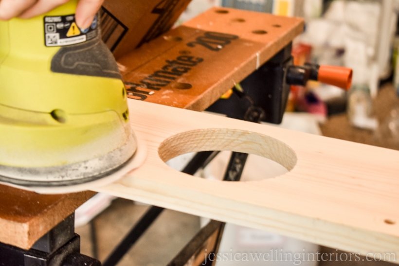 close-up of orbital sander sanding wood vertical garden shelf with holes  for faux hanging plants