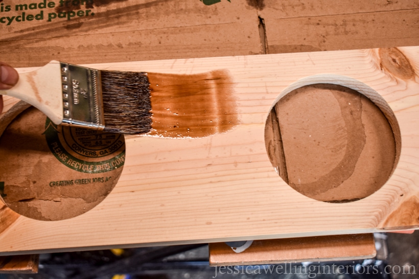 wood stain being applied with a paintbrush to vertical garden planters