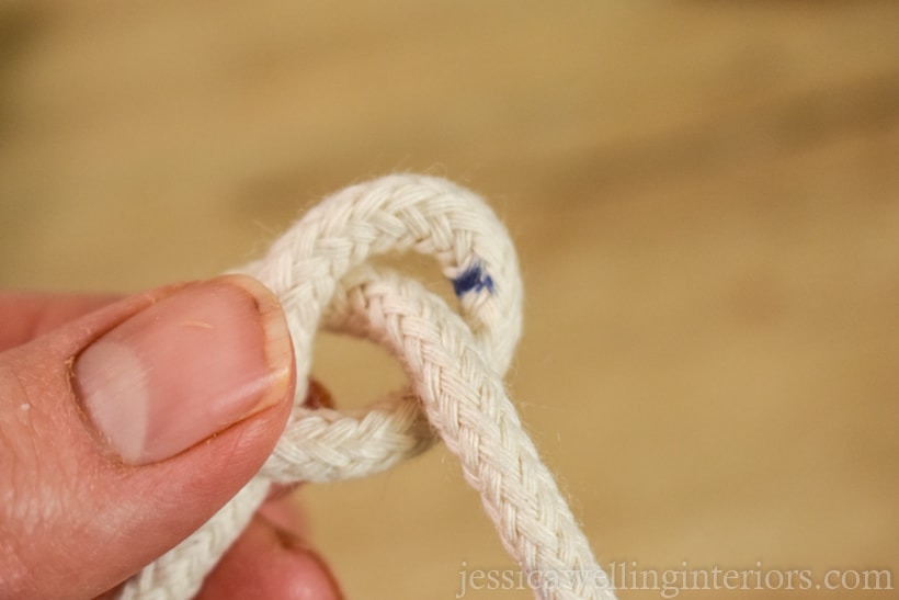 close-up of hand holding rope tied in a very loose knot to hold up an indoor vertical garden