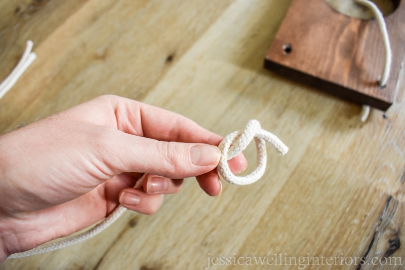 close-up of hand holding end of rope with a knot being tied to hang a  diy vertical garden planter