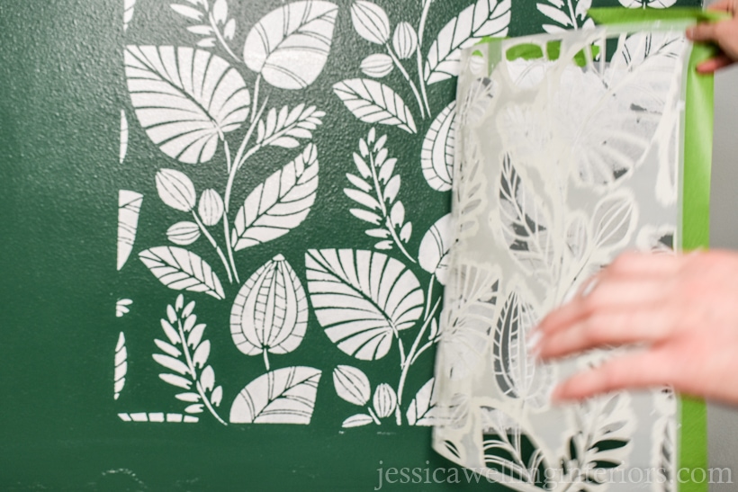 hands removing a large wall stencil from the wall