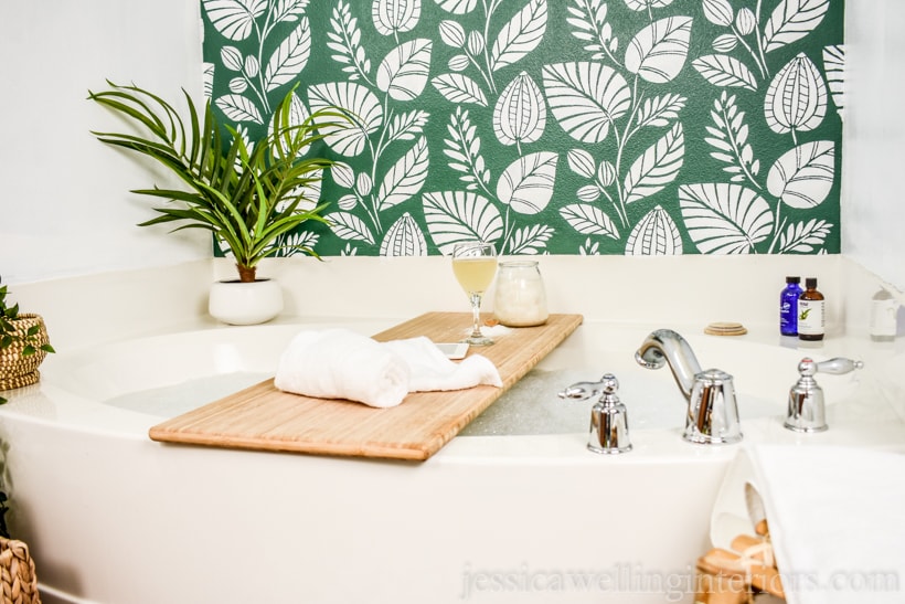 after photo of a bathtub in front of a green stenciled accent wall