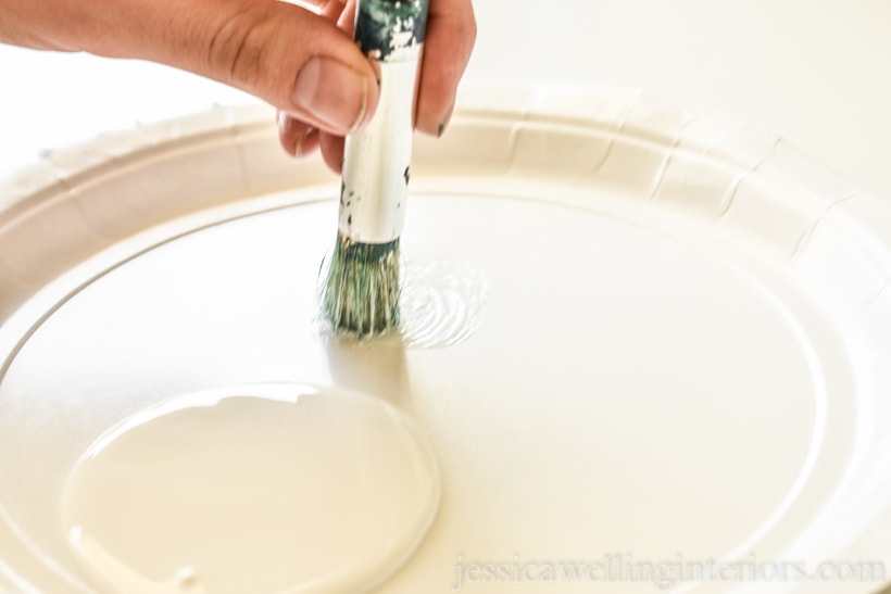 close-up of a hand swirling a stencil brush on a paper plate to off-load some of the paint before stenciling