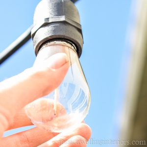 hand screwing a lightbulb into a string light socket