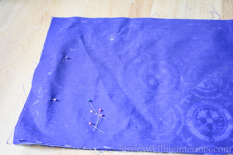 two pieces of dark blue outdoor fabric pinned with right sides together before sewing into a pillow