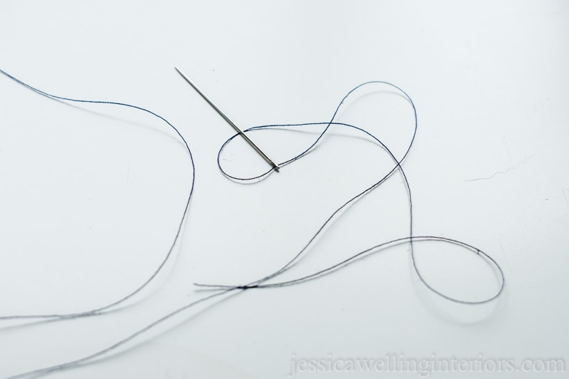 hand-sewing needle threaded with dark blue thread.