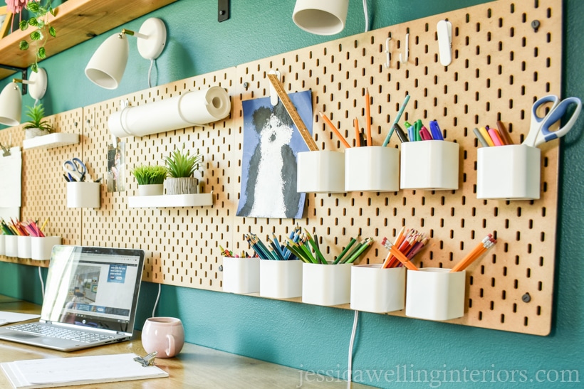 SKADIS pegboard mounted over a school desk for home with cups for pencils, scissors, and other school supplies