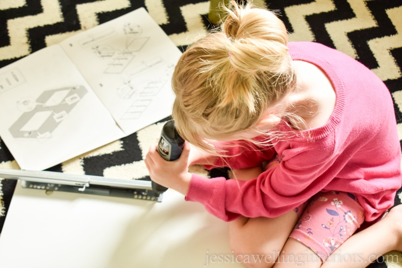 little girl using a screwdriver to assemble an Ikea Alex drawer unitl for a school desk for home