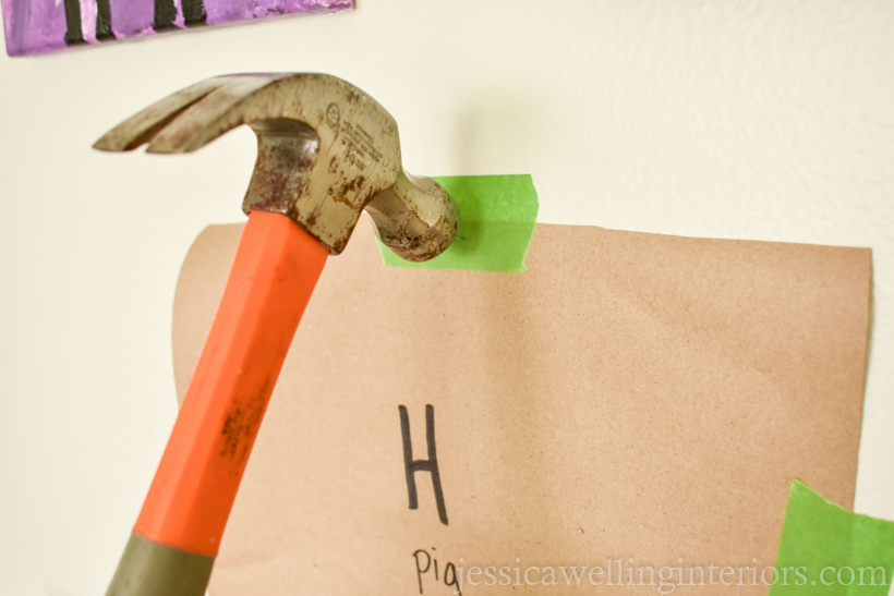 close-up of hammer pounding a nail into the wall to hang a piece of framed artwork
