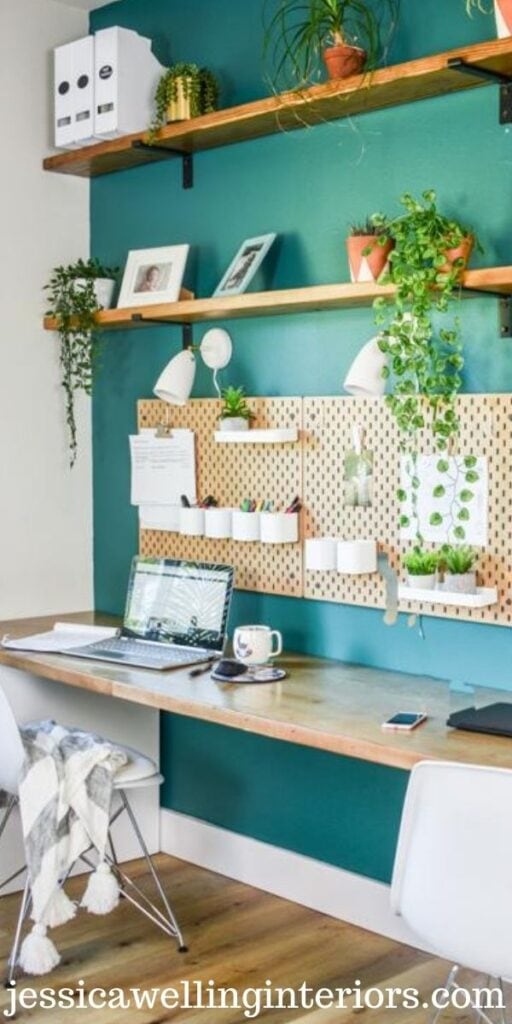 10' long Ikea desk with two workstations against a greed accent wall, with pegboards, task lights, and organizers