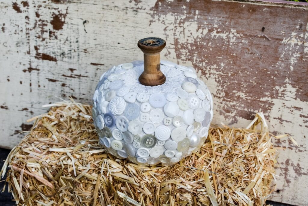 close-up of white pumpkin decor, with buttons sitting on a hay bale