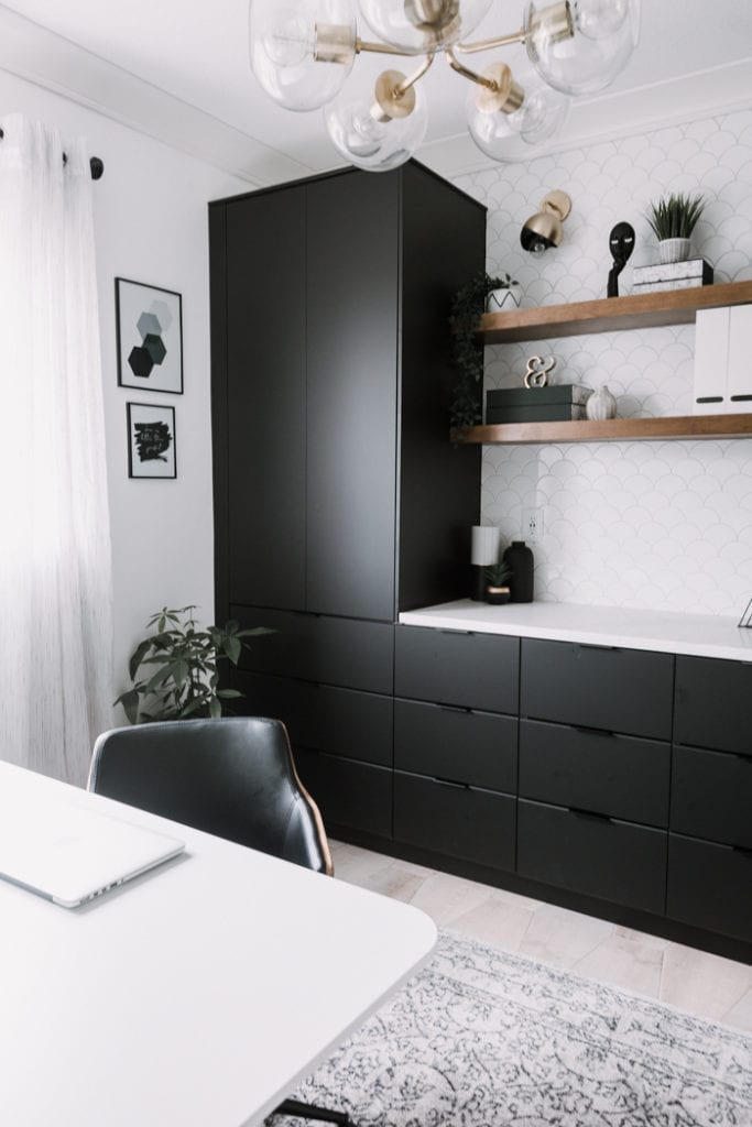 Ikea home office with black cabinetry, floating shelves, and a mermaid scale  tile wall