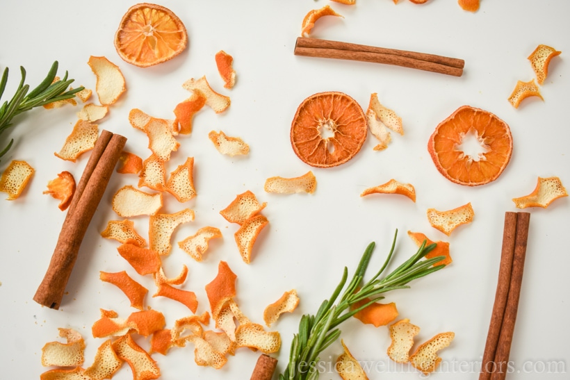 bits of dried orange peel, cinnamon sticks, and rosemary sprigs on a white background