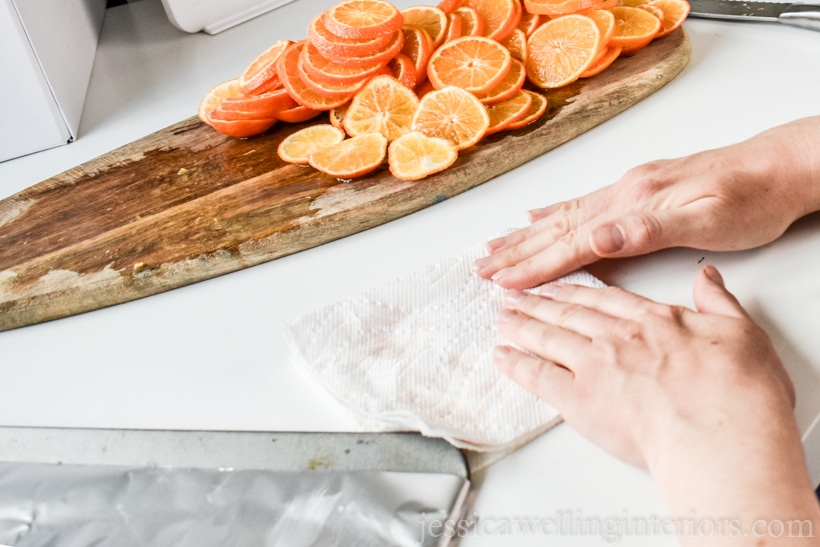 hands patting orange slices dry with a paper towel