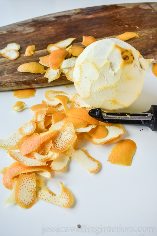 orange peeled with a potato peeler and pieces of orange peel in the background