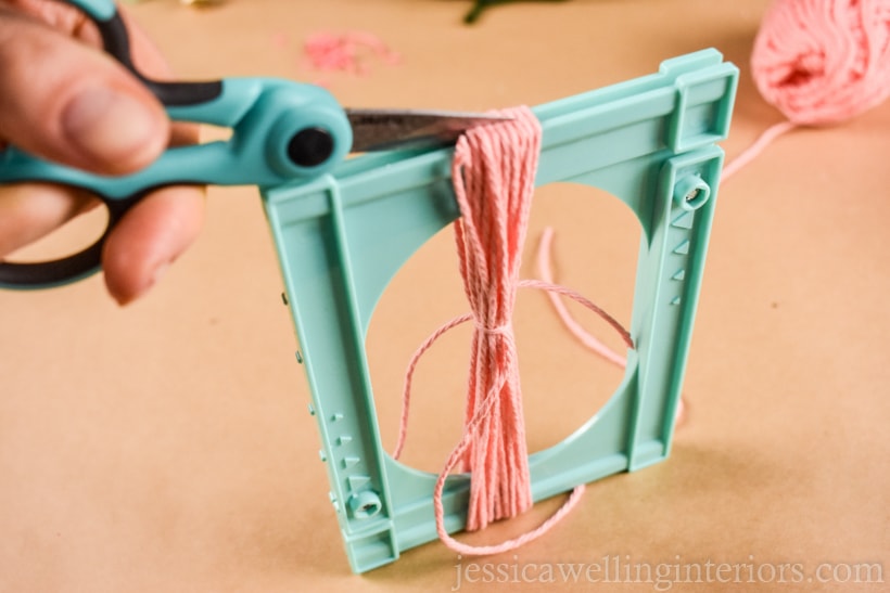 hands using scissors to cut yarn tassel ends