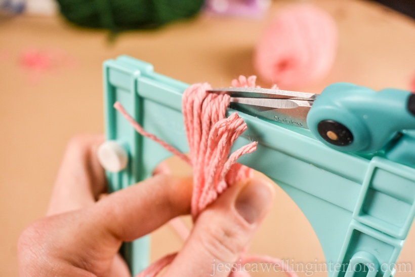 close-up of scissors cutting the ends of yarn to make a DIY tassel