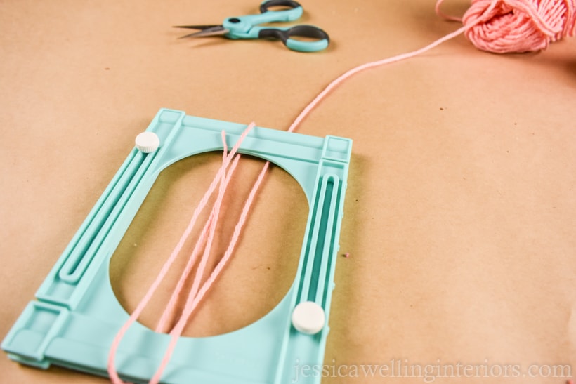 close-up of tassel maker being wrapped with pink yarn